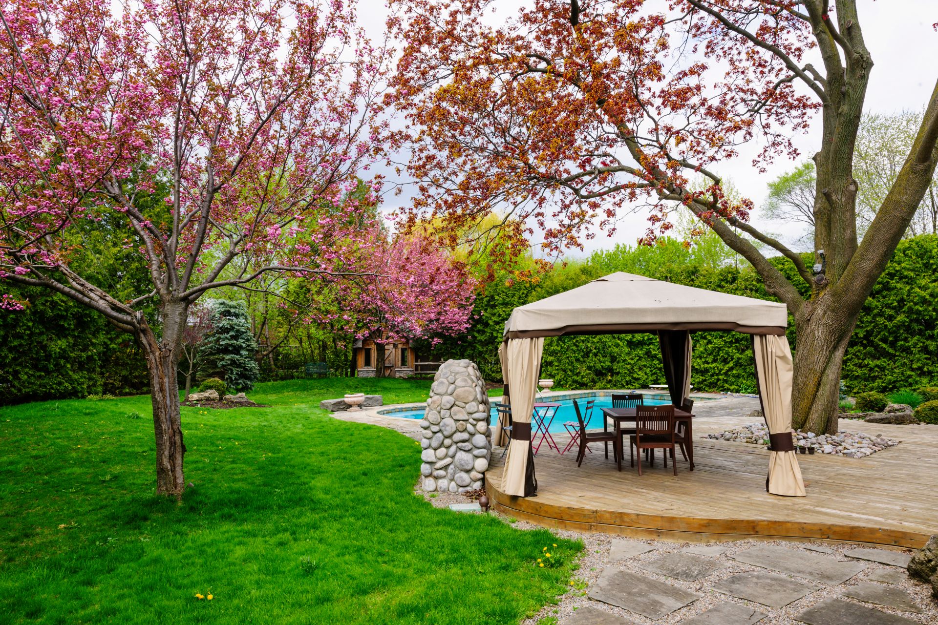 Freistehender Pavillon am Pool, umgeben von blühenden Bäumen, als luxuriöser Ort für Entspannung und Gartenfeste